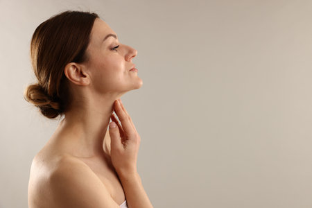 Woman touching her neck on light gray background, space for textの写真素材