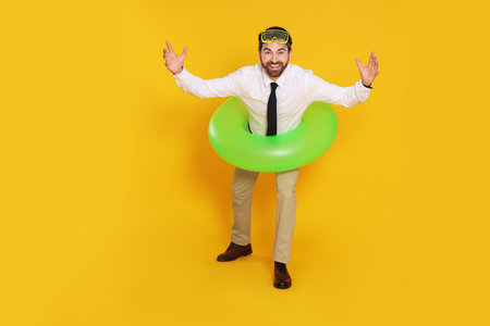 Businessman with diving mask and inflatable ring on yellow background, space for textの写真素材