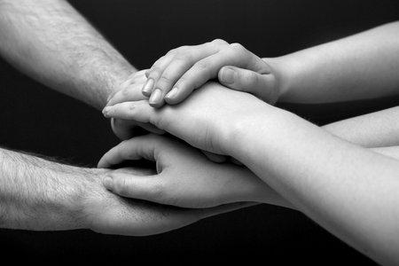 Group of people stacking their hands together, closeup. Black-and-white toningの写真素材
