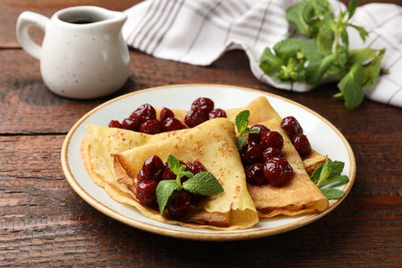 Delicious crepes served with cherry jam on wooden table, closeupの写真素材