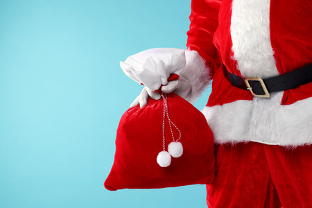 Santa Claus holding sack on light blue background, closeup with space for text. Merry Christmas and Happy New Yearの写真素材