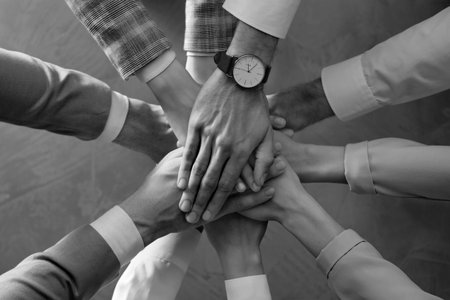 Group of people stacking their hands together, top view. Black-and-white toningの写真素材