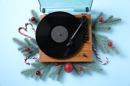 Wooden turntable with vinyl record and Christmas decor on light blue background, flat layの写真素材