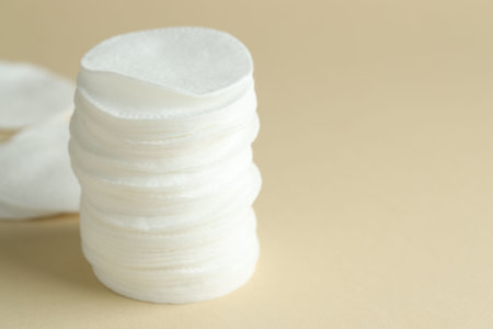 Stack of clean cotton pads on beige background, closeup. Space for textの写真素材