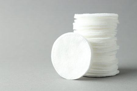 Stack of clean cotton pads on light gray background, closeup. Space for textの写真素材