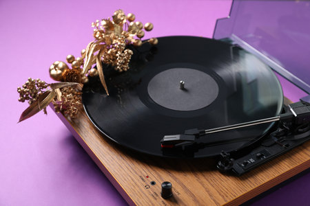 Wooden turntable with vinyl record and Christmas decor on purple background, closeupの写真素材