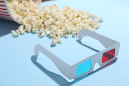 3D glasses and tasty popcorn on light blue background, closeupの写真素材