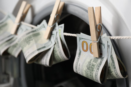 Banknotes hanging on clothesline near washing machine, closeupの写真素材