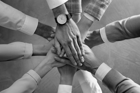Group of people stacking their hands together, top view. Black-and-white toningの写真素材