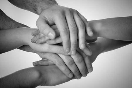 Group of people stacking their hands together, closeup. Black-and-white toningの写真素材