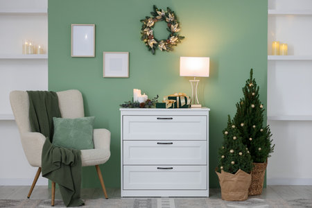 Christmas decor on white dresser and fir trees near green wall indoors. Interior designの写真素材