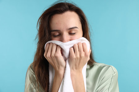 Beautiful woman with fresh towel on light blue backgroundの写真素材