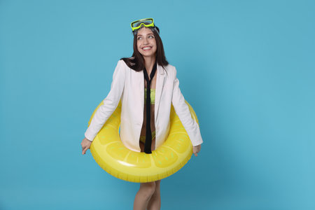 Businesswoman with diving mask and air mattress on light blue backgroundの写真素材