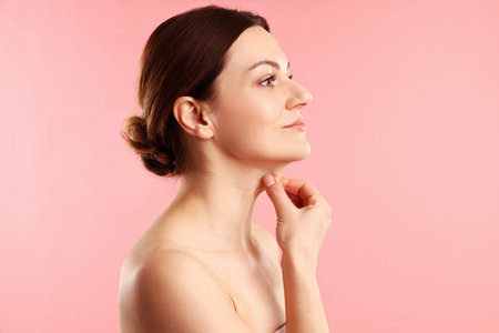 Woman touching her neck on pink background, space for textの写真素材