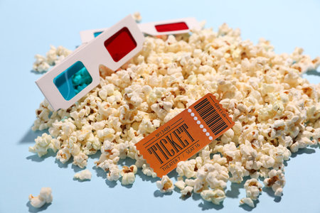 Tasty popcorn, movie ticket and 3D glasses on light blue background, closeupの写真素材