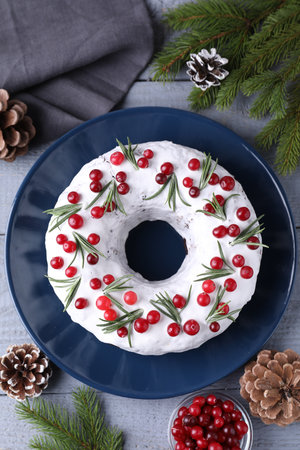 Tasty Christmas cake with cranberries, rosemary and festive decor on gray wooden table, flat layの写真素材