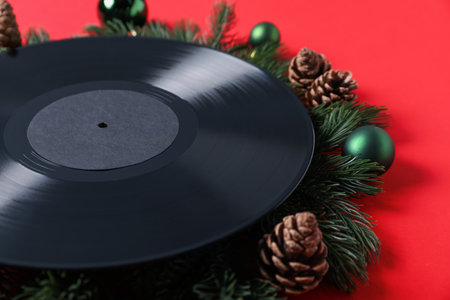 Vinyl record, fir branches, cones and baubles on red background, closeup. Christmas atmosphereの写真素材
