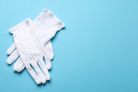 Pair of white cloth gloves on light blue background, top view. Space for textの写真素材