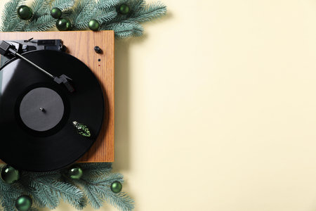 Wooden turntable with vinyl record and Christmas decor on beige background, flat lay. Space for textの写真素材