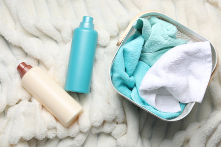 Laundry basket with towels and bottles of detergent on soft blanket, flat layの写真素材