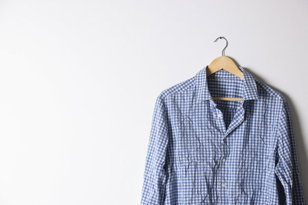 Hanger with checkered creased shirt near light wall. Space for textの写真素材