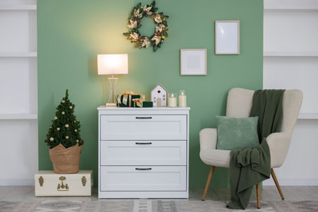 Christmas decor on white dresser and fir tree near green wall indoors. Interior designの写真素材
