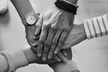 Group of people stacking their hands together, top view. Black-and-white toningの写真素材
