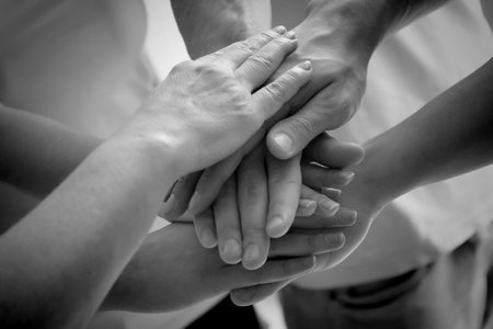 Group of people stacking their hands together, closeup. Black-and-white toningの写真素材