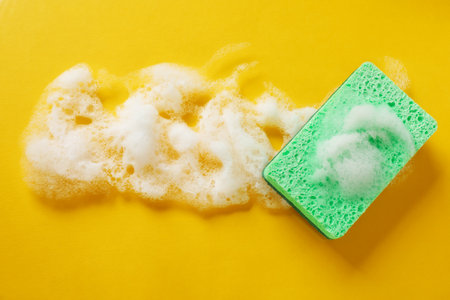 Kitchen sponge with foam on orange background, top view. Space for textの写真素材