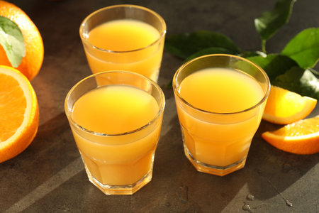 Fresh orange juice, fruits and leaves on gray table, closeupの写真素材