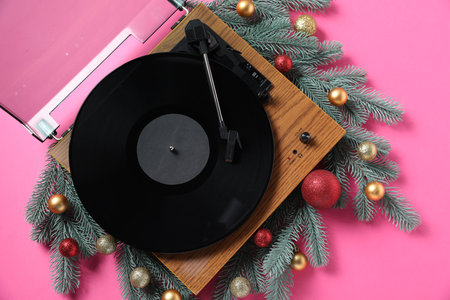 Wooden turntable with vinyl record and Christmas decor on pink background, flat layの写真素材