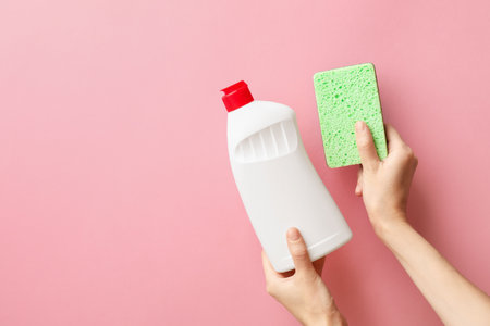 Woman holding sponge and dish soap on pink background, top view. Space for textの写真素材