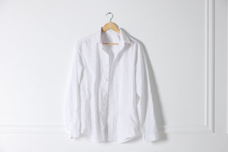 Hanger with creased shirt near white wallの写真素材