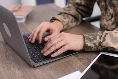 Military education. Student in soldier uniform learning at wooden desk indoors, closeupの写真素材