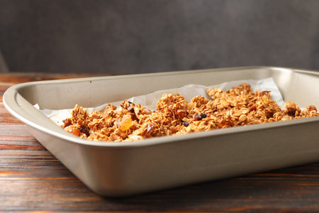 Tasty granola in tray and ingredients on wooden table, closeupの写真素材