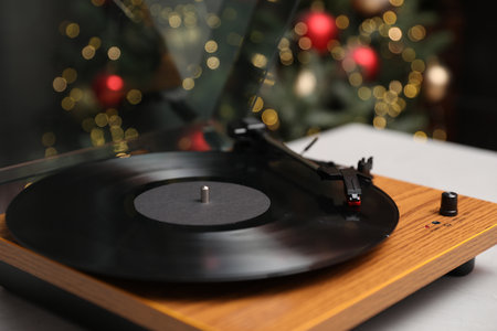 Turntable with vinyl record on table near Christmas tree, closeupの写真素材