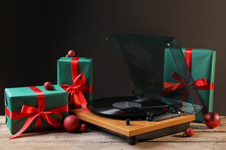 Turntable with vinyl record, gifts and Christmas decor on wooden tableの写真素材