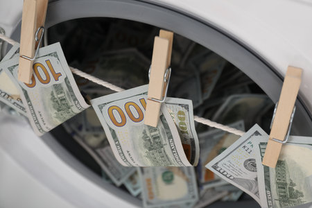 Banknotes hanging on clothesline near washing machine, closeupの写真素材