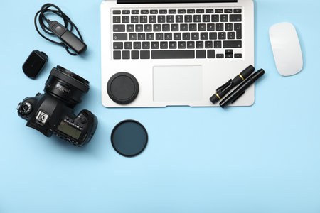 Professional photographer's equipment on light blue background, flat lay. Space for text
