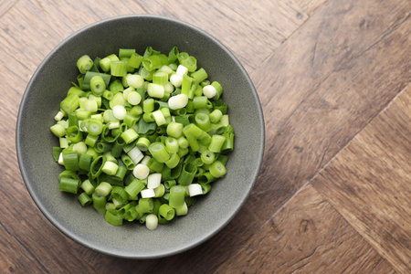 Cut green onion in bowl on wooden table, top view. Space for textの写真素材