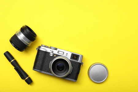 Professional photographer's equipment on yellow background, flat lay. Space for text