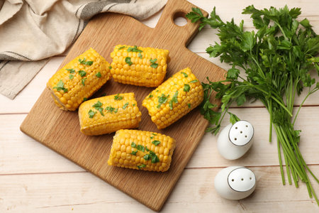 Pieces of boiled corncobs with parsley on wooden table, flat layの写真素材