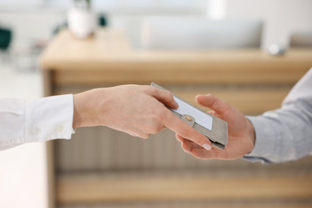Receptionist giving passport and hotel key card to guest indoors, closeupの写真素材