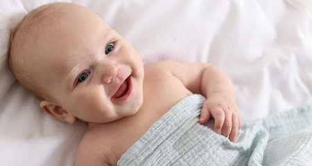 Cute newborn baby wrapped with blanket on bed, above viewの写真素材