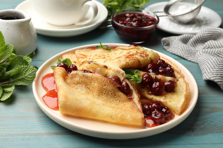Delicious crepes with cherry jam served on light wooden table, closeupの写真素材