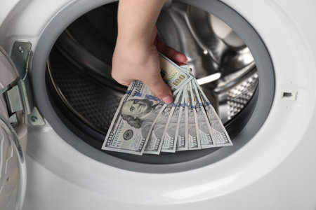 Woman putting dollar banknotes into washing machine, closeupの写真素材