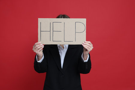 Businesswoman holding sign with word Help on red backgroundの写真素材