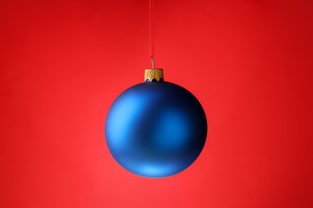 One Christmas ball hanging against red background, closeupの写真素材