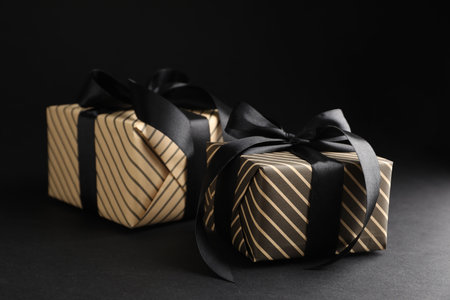 Beautiful wrapped gift boxes on black background, closeup