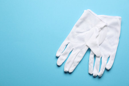 Pair of white cloth gloves on light blue background, top view. Space for textの写真素材